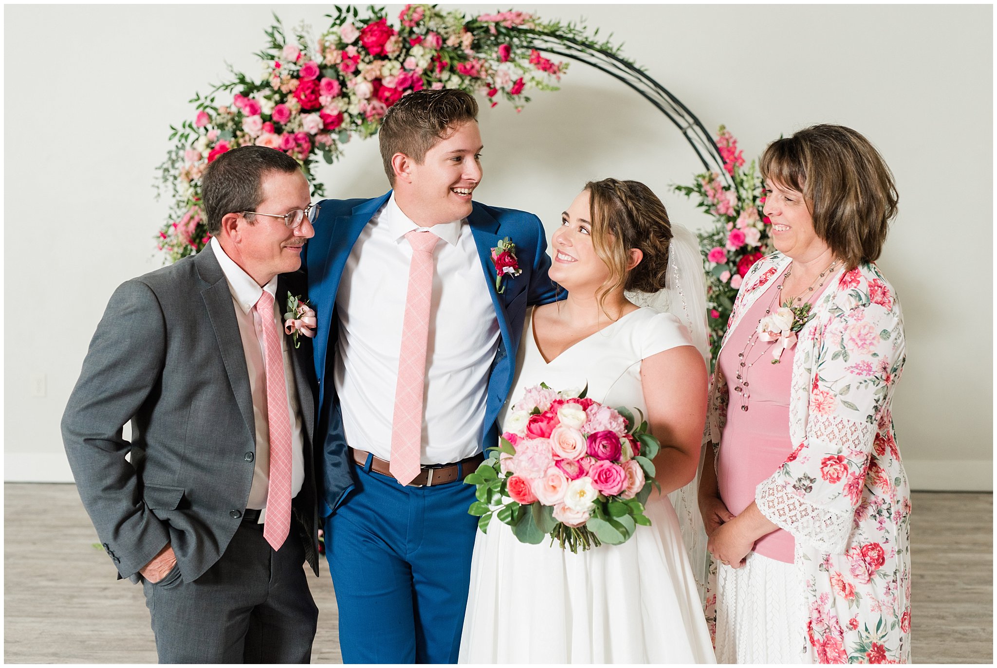 Family portraits in front of floral arch in shades of pink | Talia Event Center Summer Wedding | Jessie and Dallin Photography