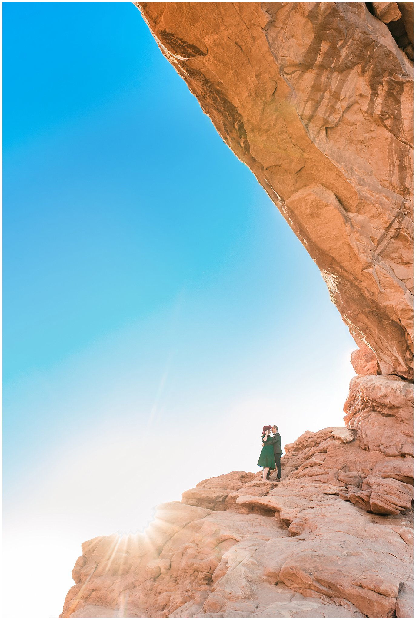 Couple dressed in green dress and grey and blue suit with bowtie for adventure engagement session at Arches National Park and Dead Horse Point Engagement | Jessie and Dallin Photography