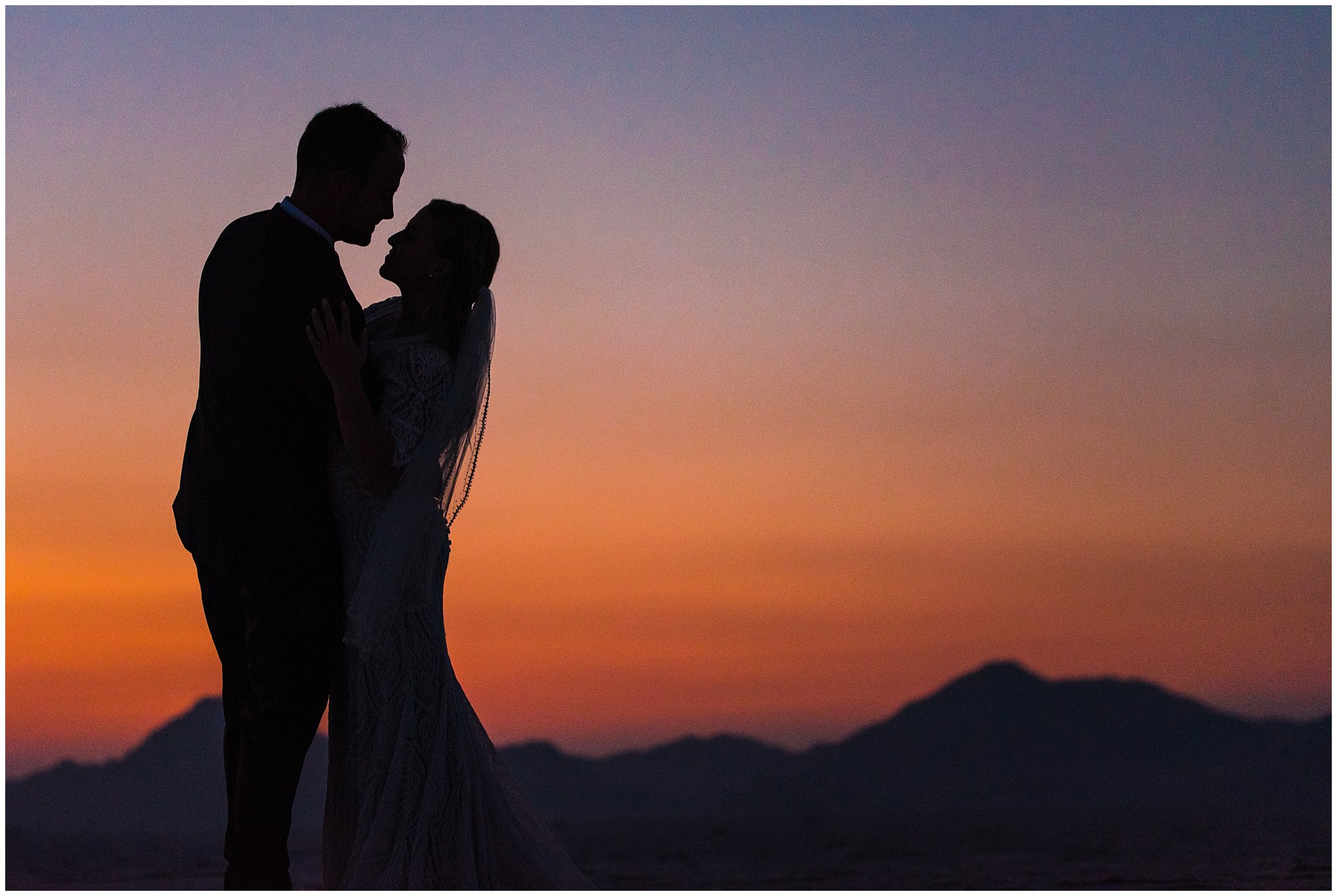 Bride and Groom silhouette at sunset in lace detail dress and blue suit for Adventure Session | Bonneville Salt Flats Sunset Wedding Formal Session | Jessie and Dallin Photography