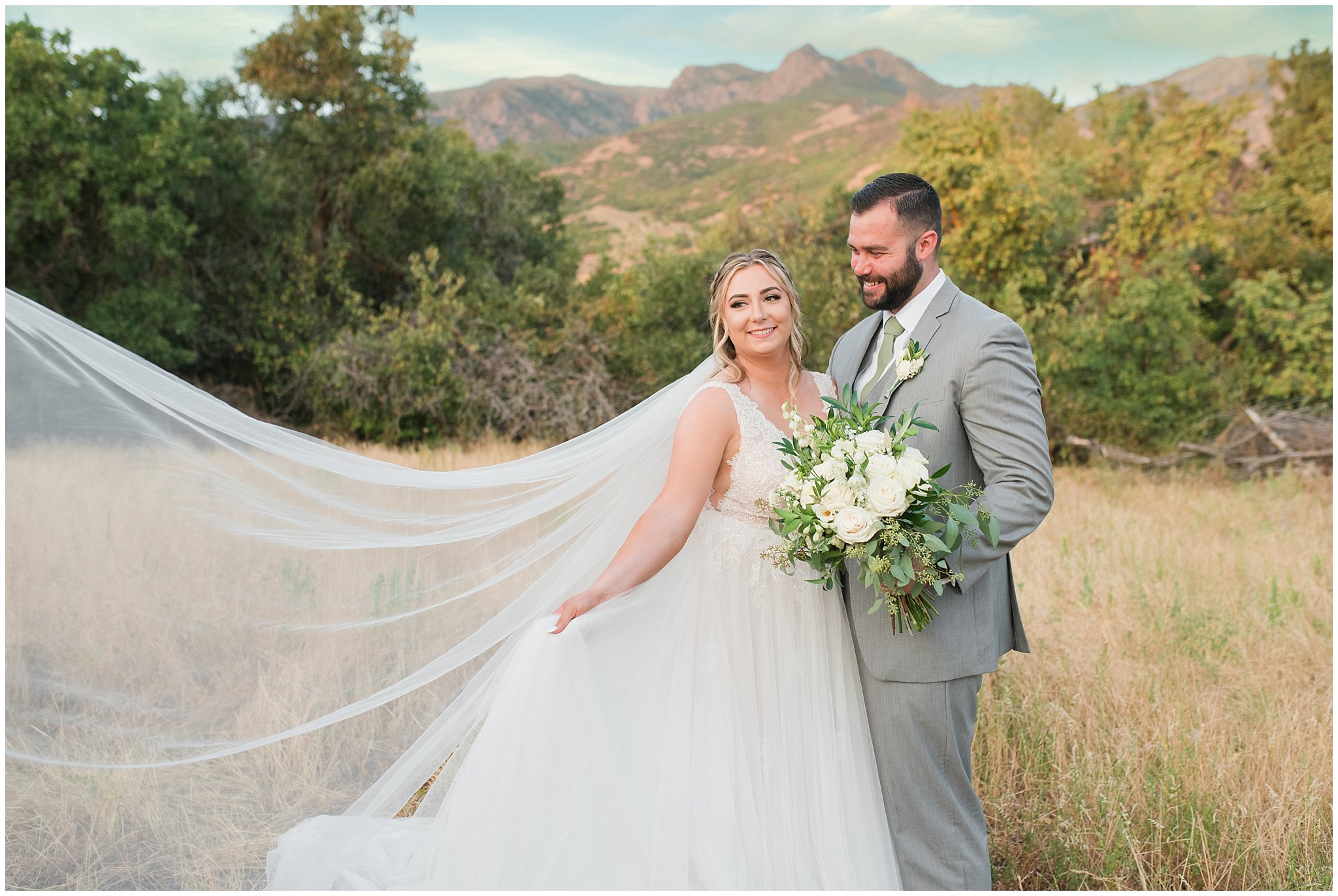 Bride and groom portraits with gray suit and champagne dress and veil and white floral bouquet in the Utah mountains | Sage Green and Gray Summer Wedding at Oak Hills | Jessie and Dallin Photography