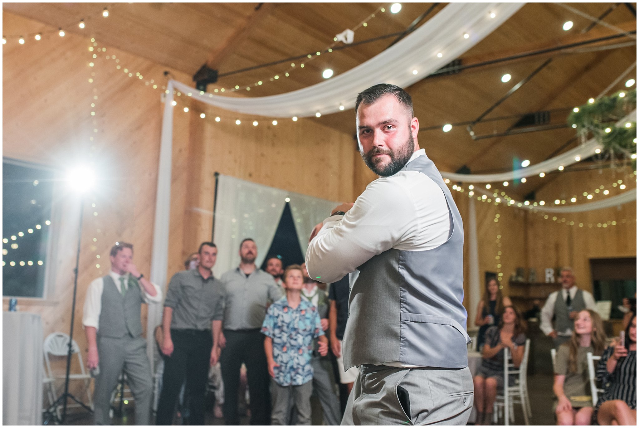 Garter toss in a barn during wedding reception | Sage Green and Gray Summer Wedding at Oak Hills | Jessie and Dallin Photography