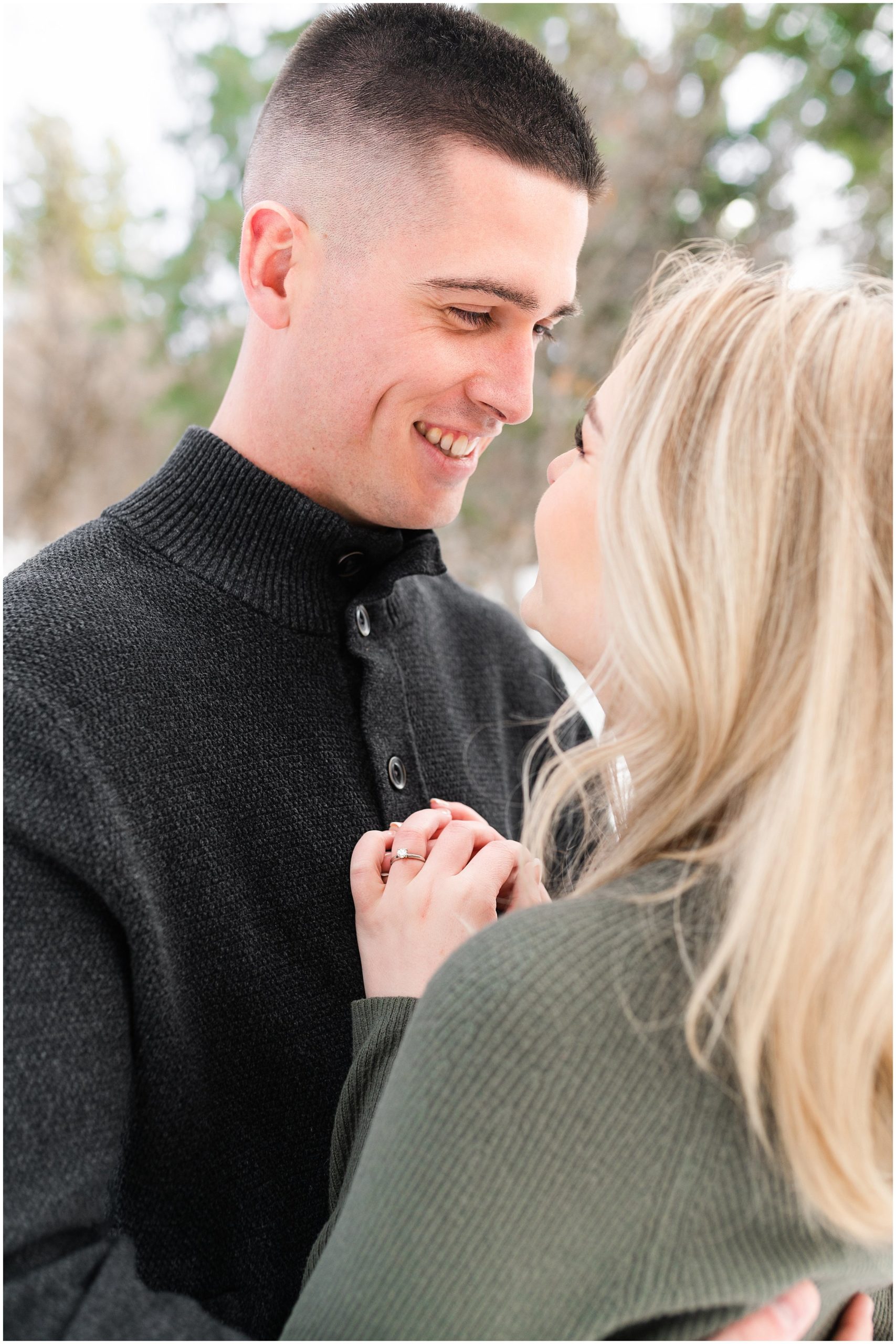 Couple in the snow during mountain destination engagement session in Utah | Wearing olive colored dress with black floppy hat and black sweater and black pants | Snowbasin Resort Snowy Engagement Session | Jessie and Dallin Photography