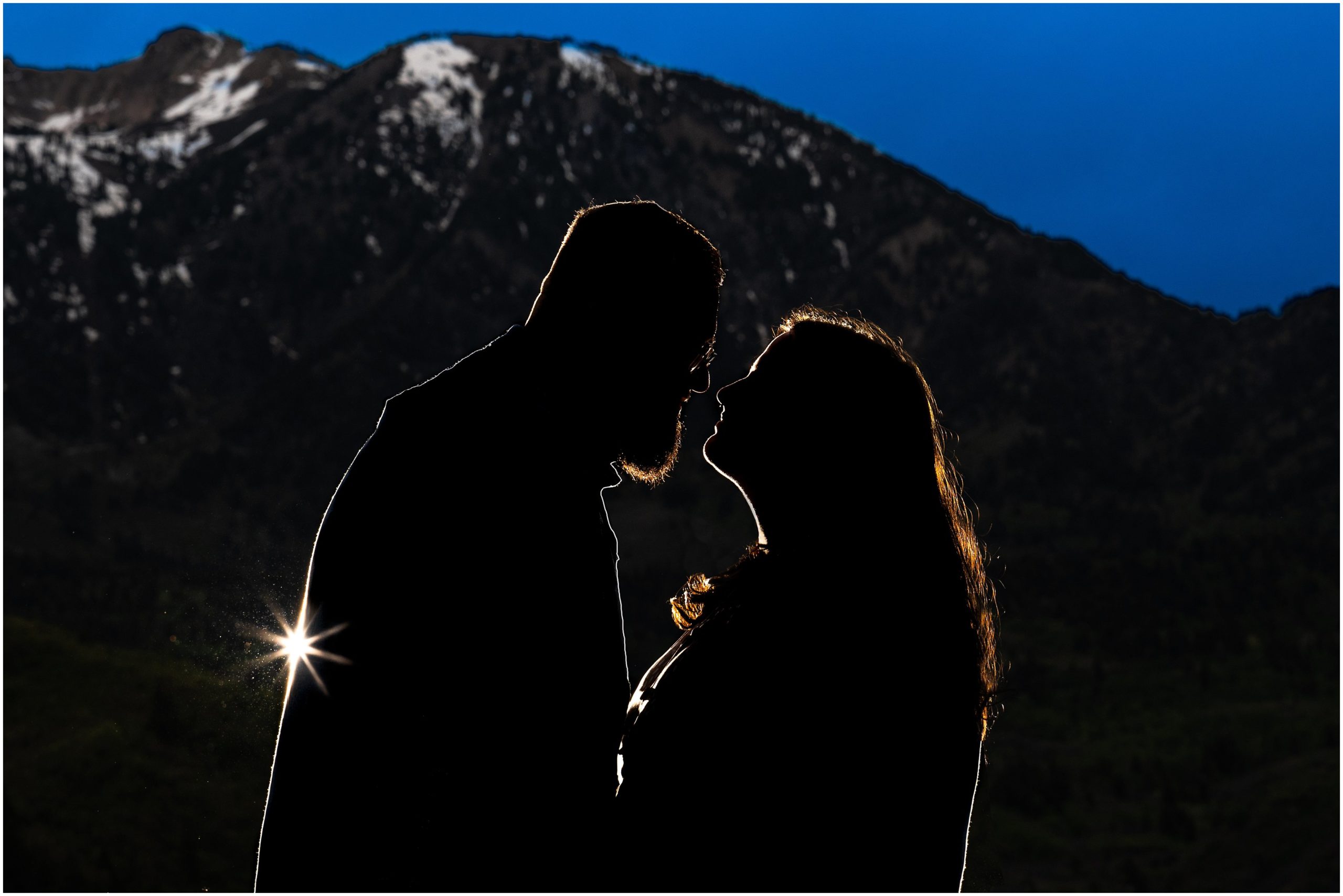 Silhouette of a couple during engagement session in yellow sunflower wildflowers surrounded by snowy mountain peaks | Ogden Valley Summer Engagement Session