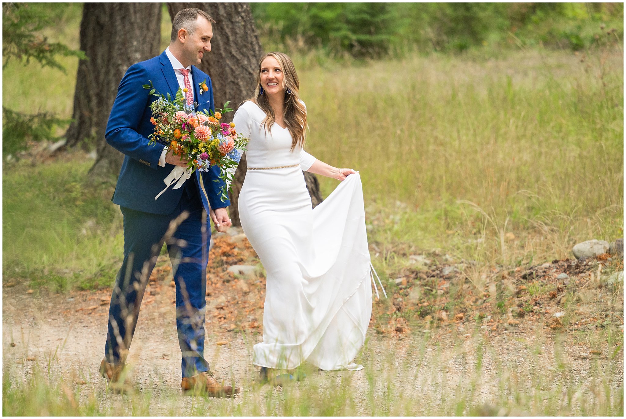 Bride and groom portraits with an elegant fitted dress and blue suit with coral tie, and wildflower bouquet in the Montana forest and near a pond | Mountainside Weddings Kalispell Montana Destination Wedding | Jessie and Dallin Photography