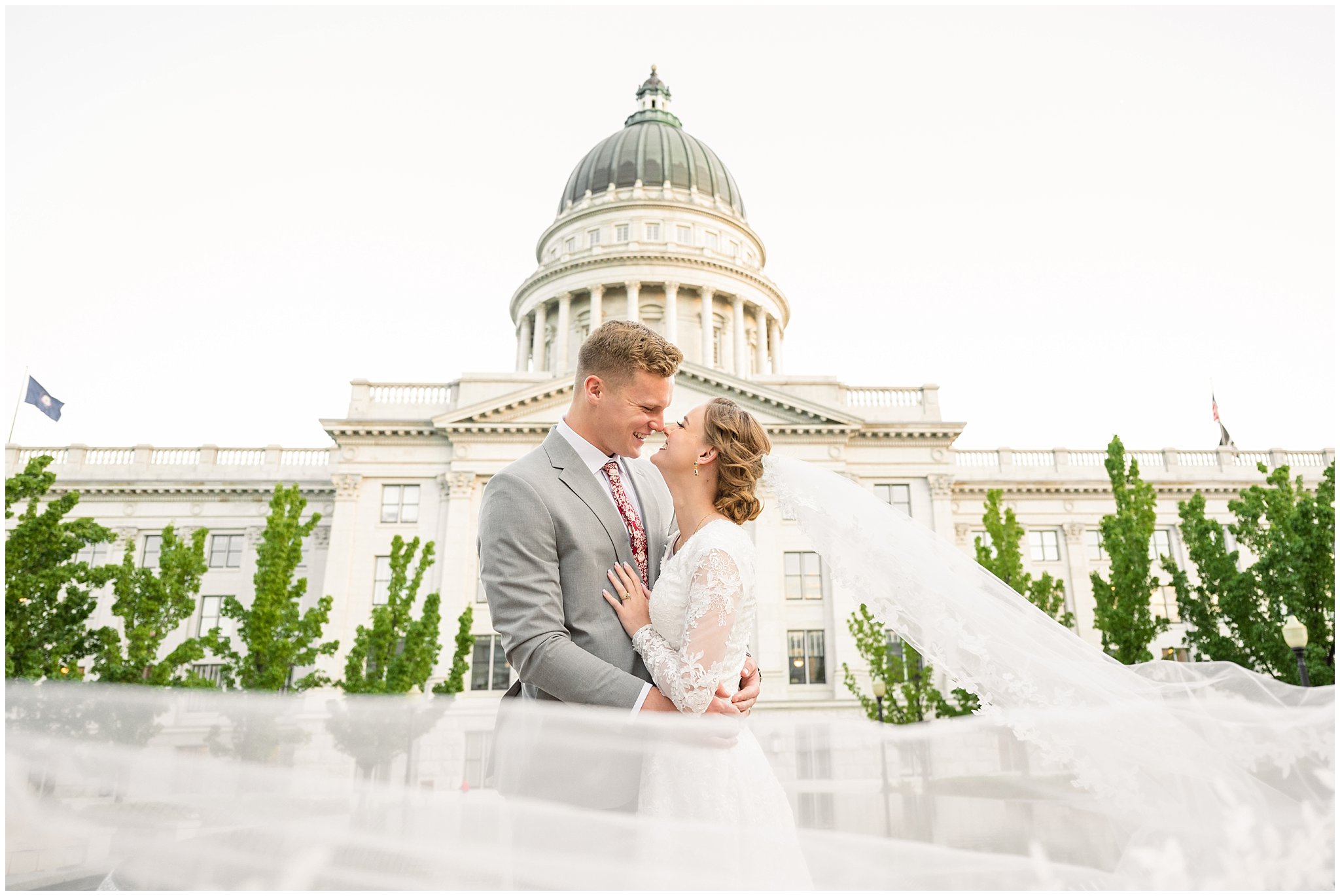 Bride and groom with long cathedral length veil with the Utah State Capitol behind them | Sunset Utah State Capitol Wedding Formal Session | Jessie and Dallin Photography