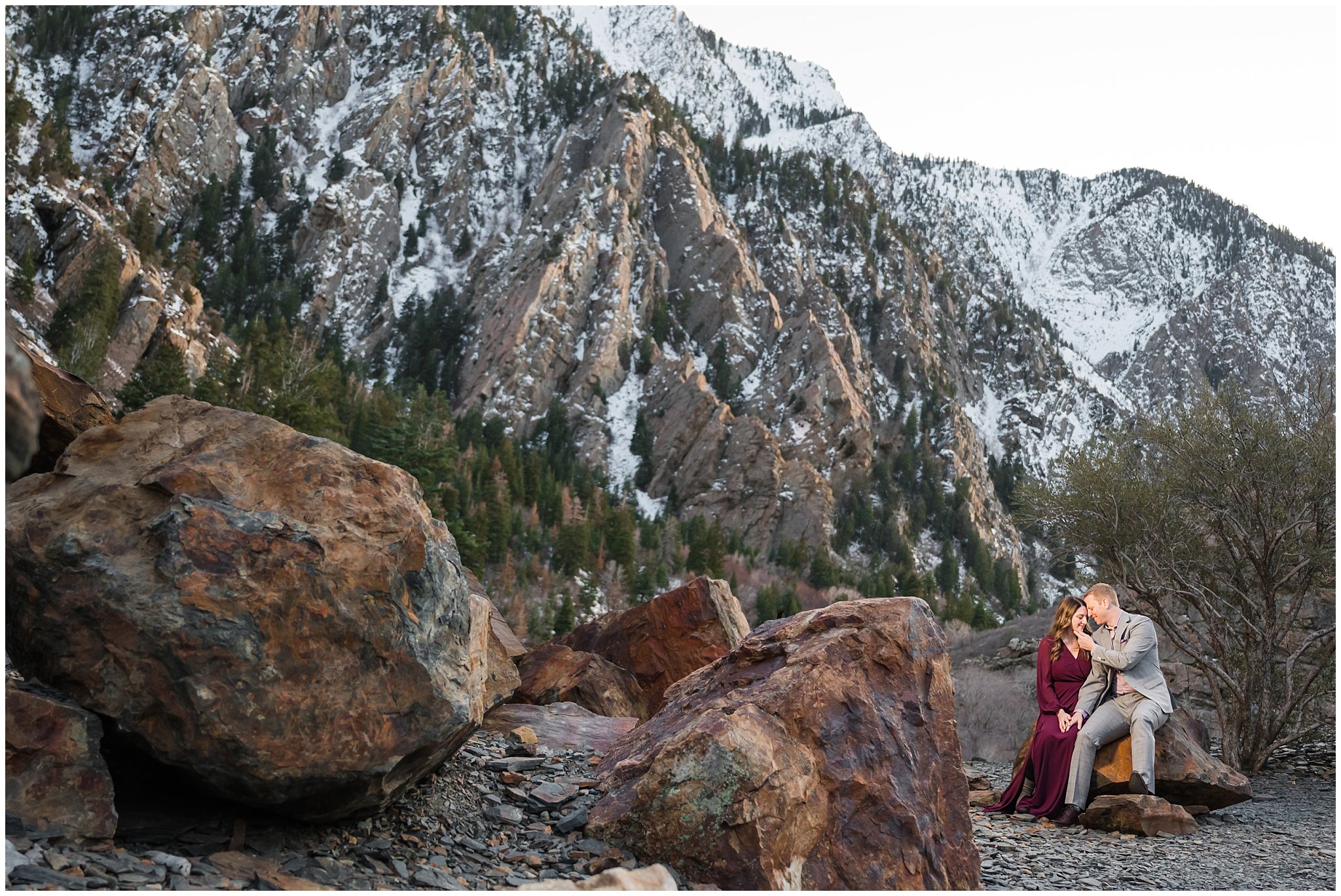 Couple dressed up in formal outfits sharing candid moments in the Utah mountains in the snow | Big Cottonwood Canyon Winter Engagement Session | Jessie and Dallin Photography