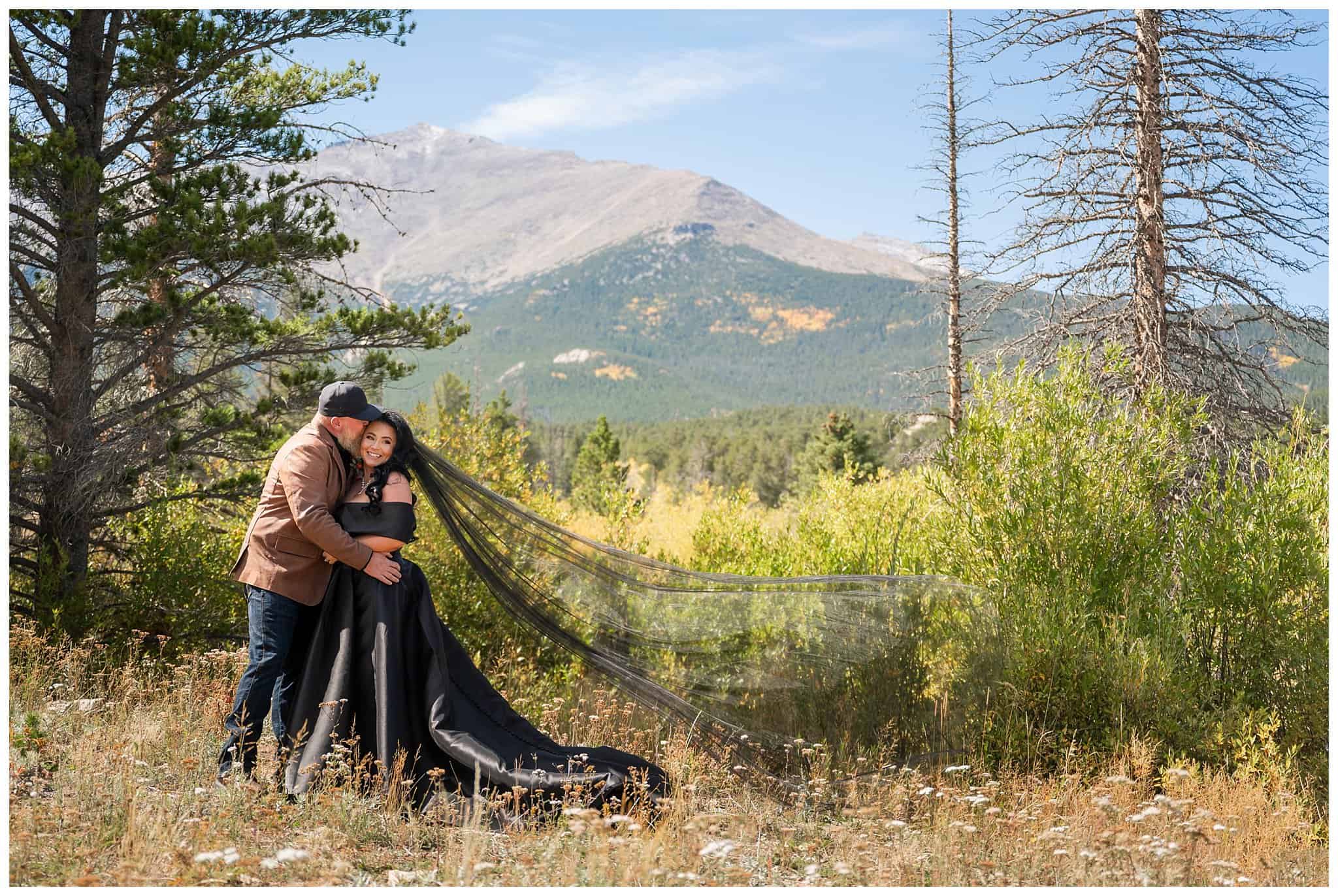 Bride in black wedding dress and veil and groom in leather brown jacket and hat share moments together outside of the Church on the Rock at Estes Park | Fall Rocky Mountain National Park Elopement | Jessie and Dallin Photography