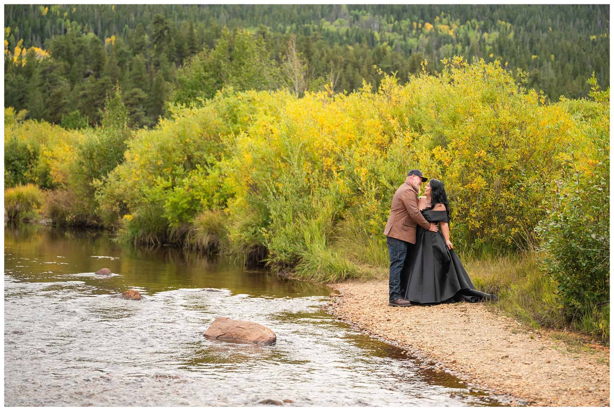 Bride in black dress and groom in brown leather jacket sharing moments next to a river at Rocky National Park | Fall Rocky Mountain National Park Elopement | Jessie and Dallin Photography