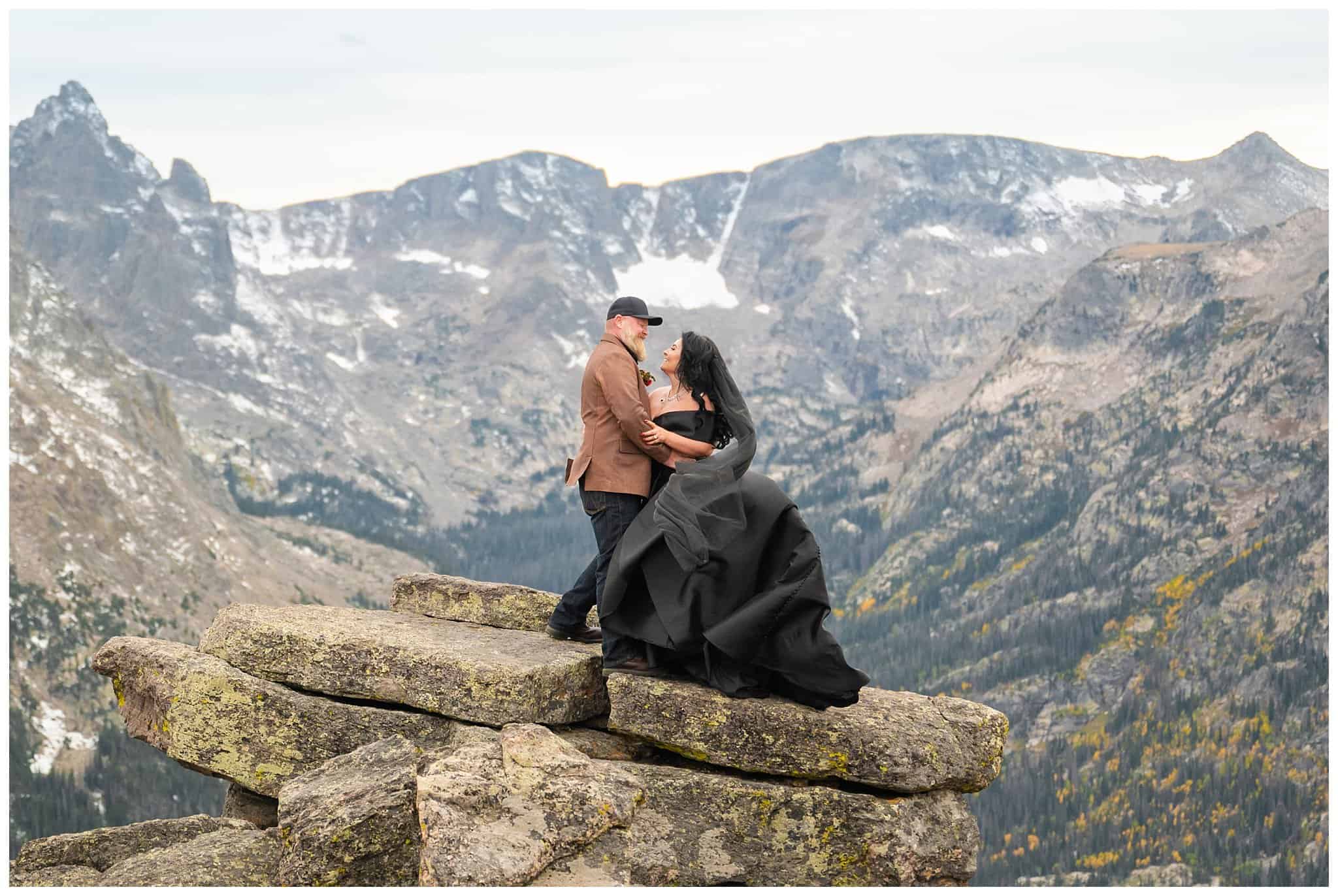 Bride in black dress and groom in brown leather jacket sharing moments in the windy tundra at Rocky National Park | Fall Rocky Mountain National Park Elopement | Jessie and Dallin Photography