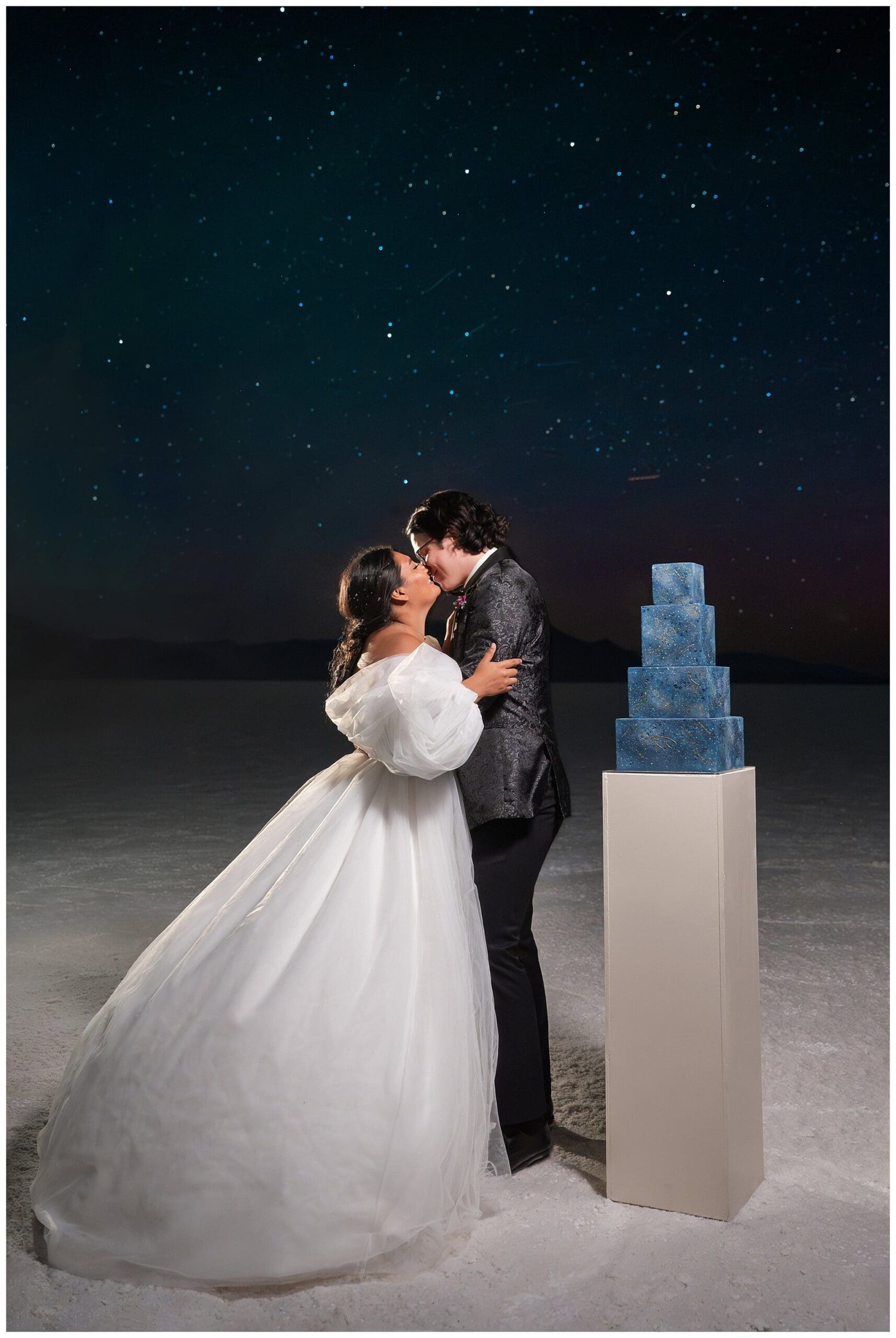 Bride and Groom share a moment beneath the stars with a four-tier constellation cake that glows in the dark at the Bonneville Salt Flats during inspiration elopement | Jessie and Dallin Photography