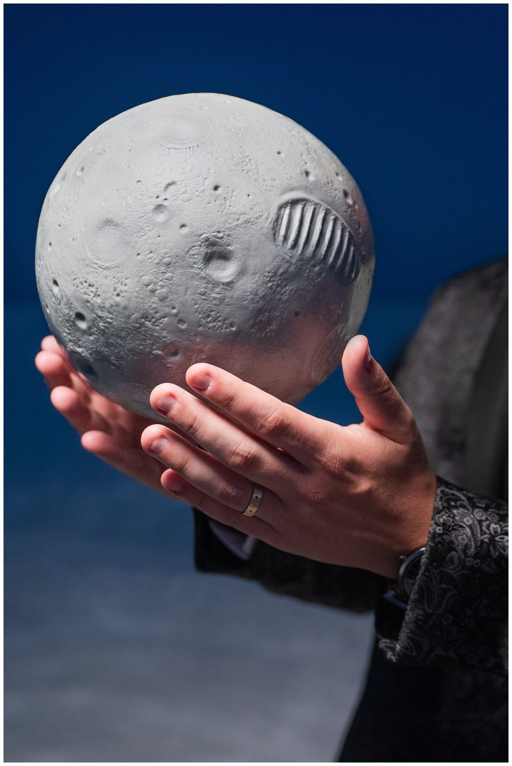 Groom holds a floating moon landing cake that glows in the dark at the Bonneville Salt Flats during inspiration elopement | Jessie and Dallin Photography