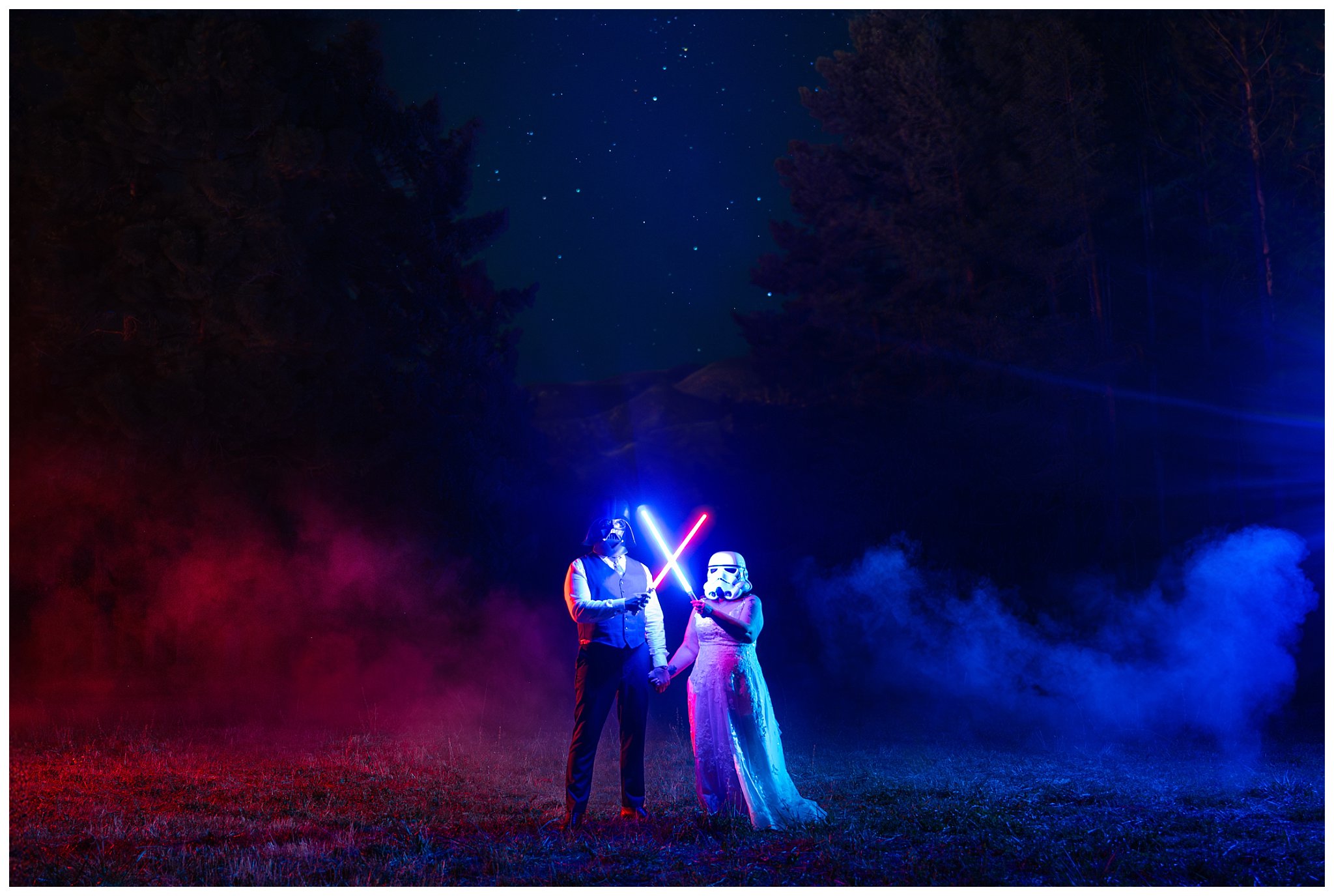 Bride and groom wearing Darth Vader and Stormtrooper helmets and holding lightsabers at night under the stars in red and blue smoke | Star Wars Themed Wedding at Oak Hills Utah | Jessie and Dallin Photography