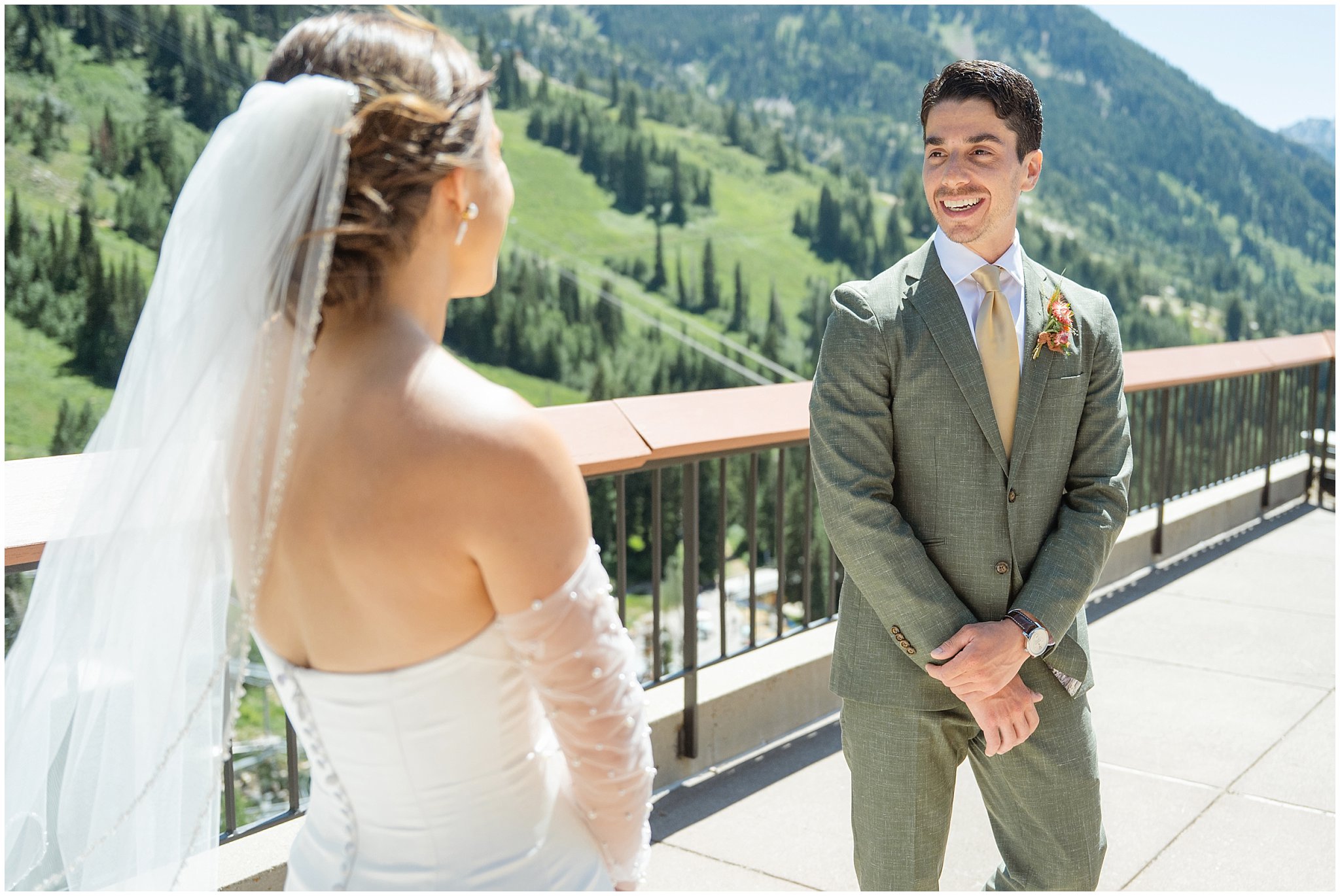 Bride and groom sharing a first look on the rooftop of The Cliff Lodge. Groom wearing a sage green suit and golden tie, bride in a strapless dress with gloves and veil | Snowbird Summit Summer Wedding | Jessie and Dallin Photography