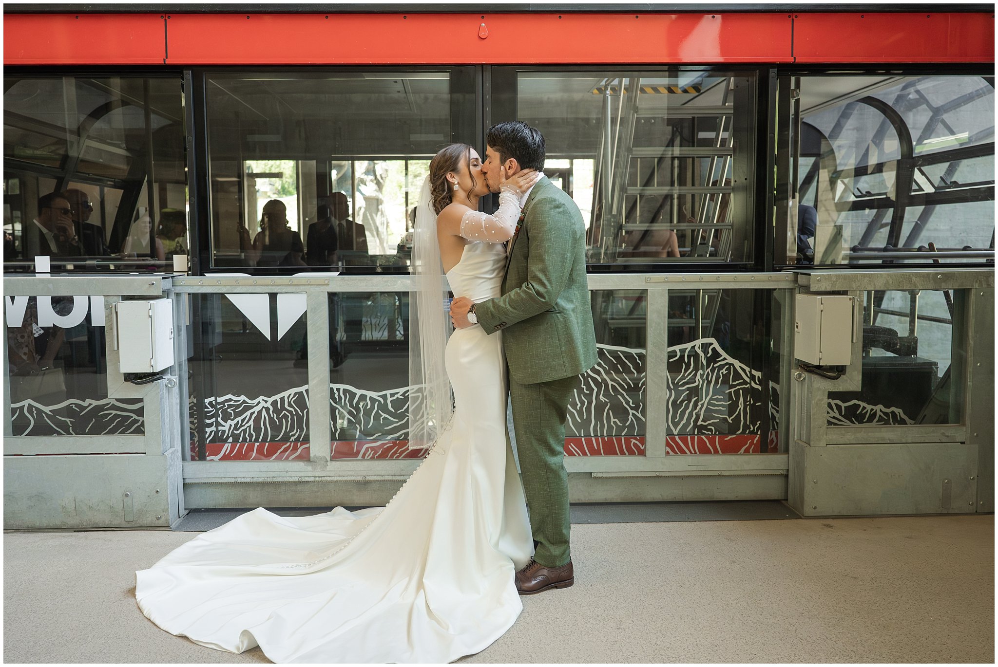 Bride and groom share a moment next to the tram before their ceremony. Groom wearing a sage green suit and golden tie, bride in a strapless dress with gloves and veil | Snowbird Summit Summer Wedding | Jessie and Dallin Photography