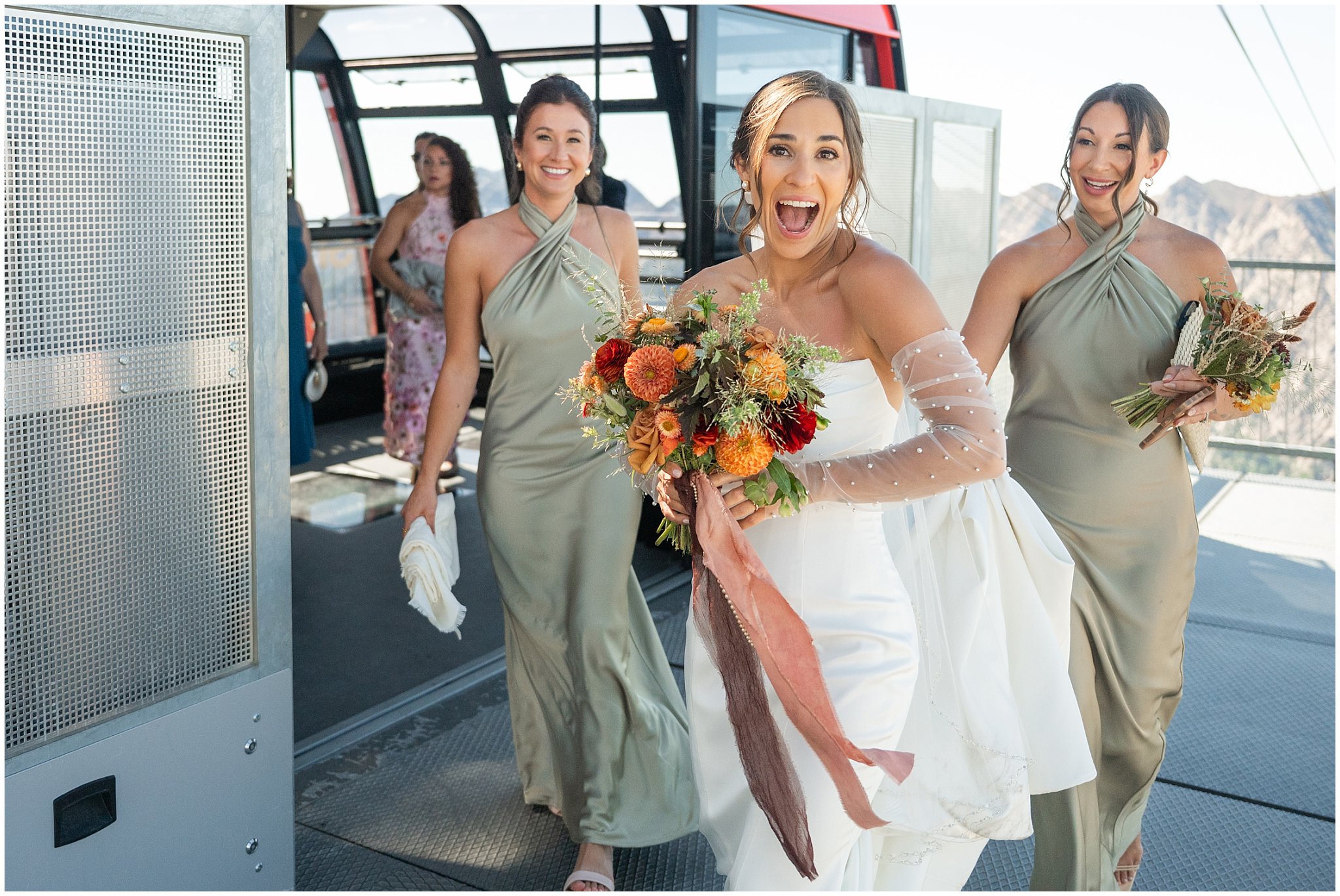 Bride laughs as she exits the Snowbird tram. Groom wearing a sage green suit and golden tie, bride in a strapless dress with gloves and veil | Snowbird Summit Summer Wedding | Jessie and Dallin Photography