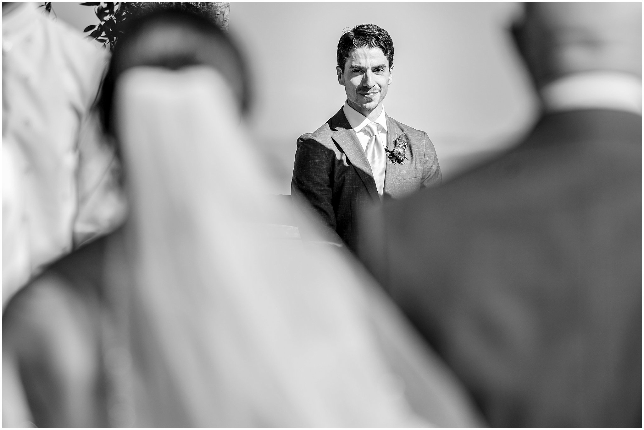 Groom looking emotional as he sees bride walking down the aisle. Groom wearing a sage green suit and golden tie, bride in a strapless dress with gloves and veil | Snowbird Summit Summer Wedding | Jessie and Dallin Photography