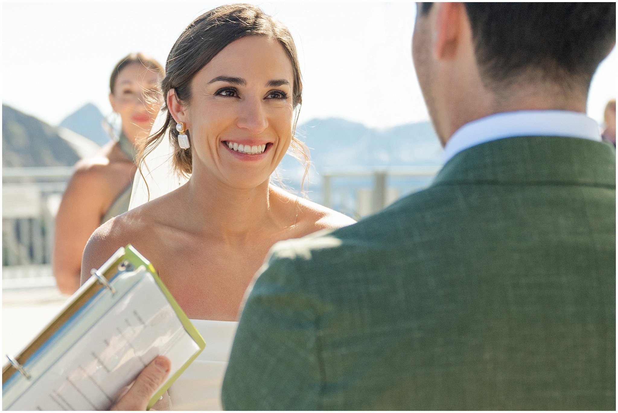 Bride laughing at the top of the aisle during ceremony. Groom wearing a sage green suit and golden tie, bride in a strapless dress with gloves and veil | Snowbird Summit Summer Wedding | Jessie and Dallin Photography