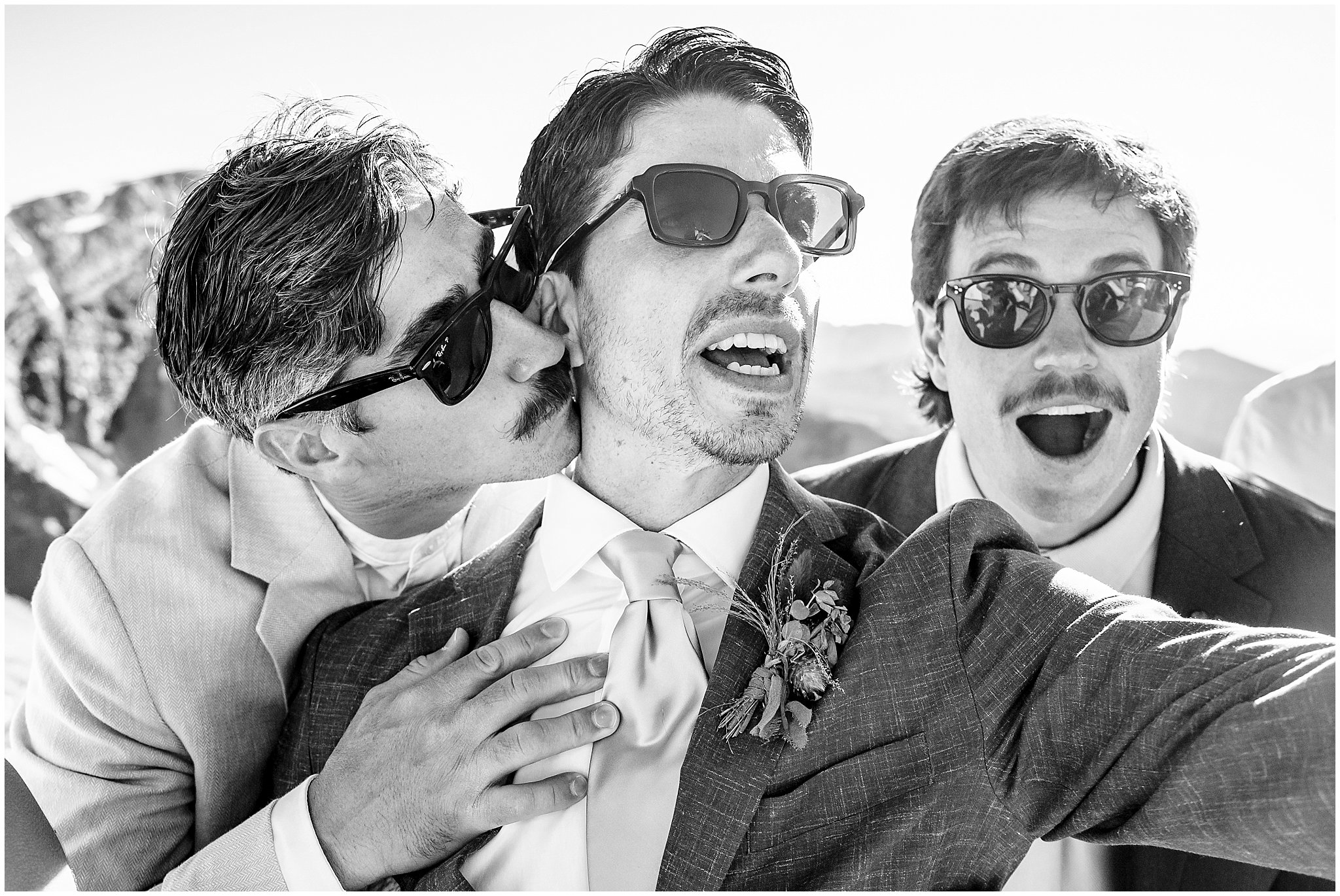 Bride and groom do funny poses with friends on top of the mountain. Groom wearing a sage green suit and golden tie, bride in a strapless dress with gloves and veil | Snowbird Summit Summer Wedding | Jessie and Dallin Photography