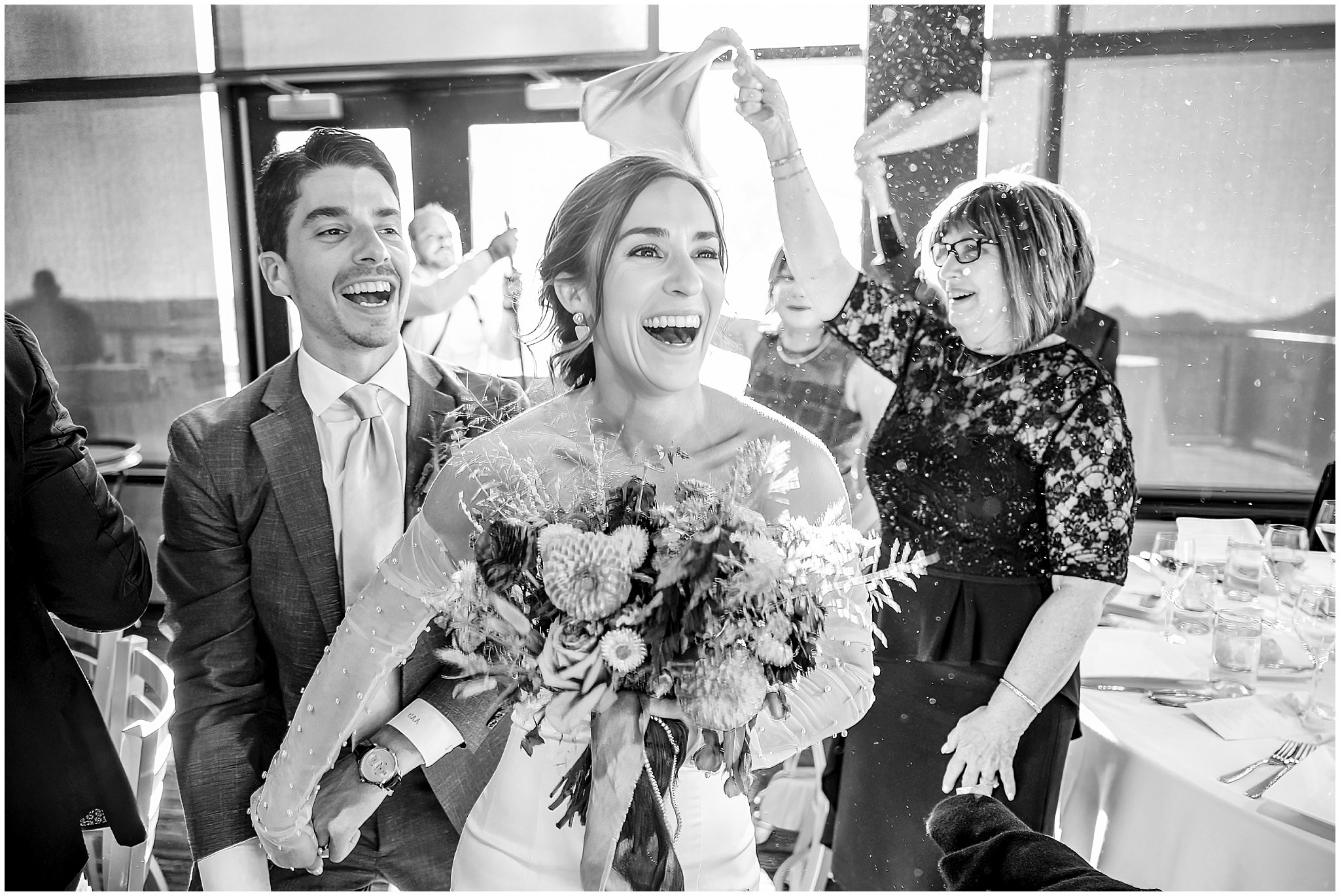 Bride and groom run celebrating through their guests to dinner during their grand entrance. Groom wearing a sage green suit and golden tie, bride in a strapless dress with gloves and veil | Snowbird Summit Summer Wedding | Jessie and Dallin Photography