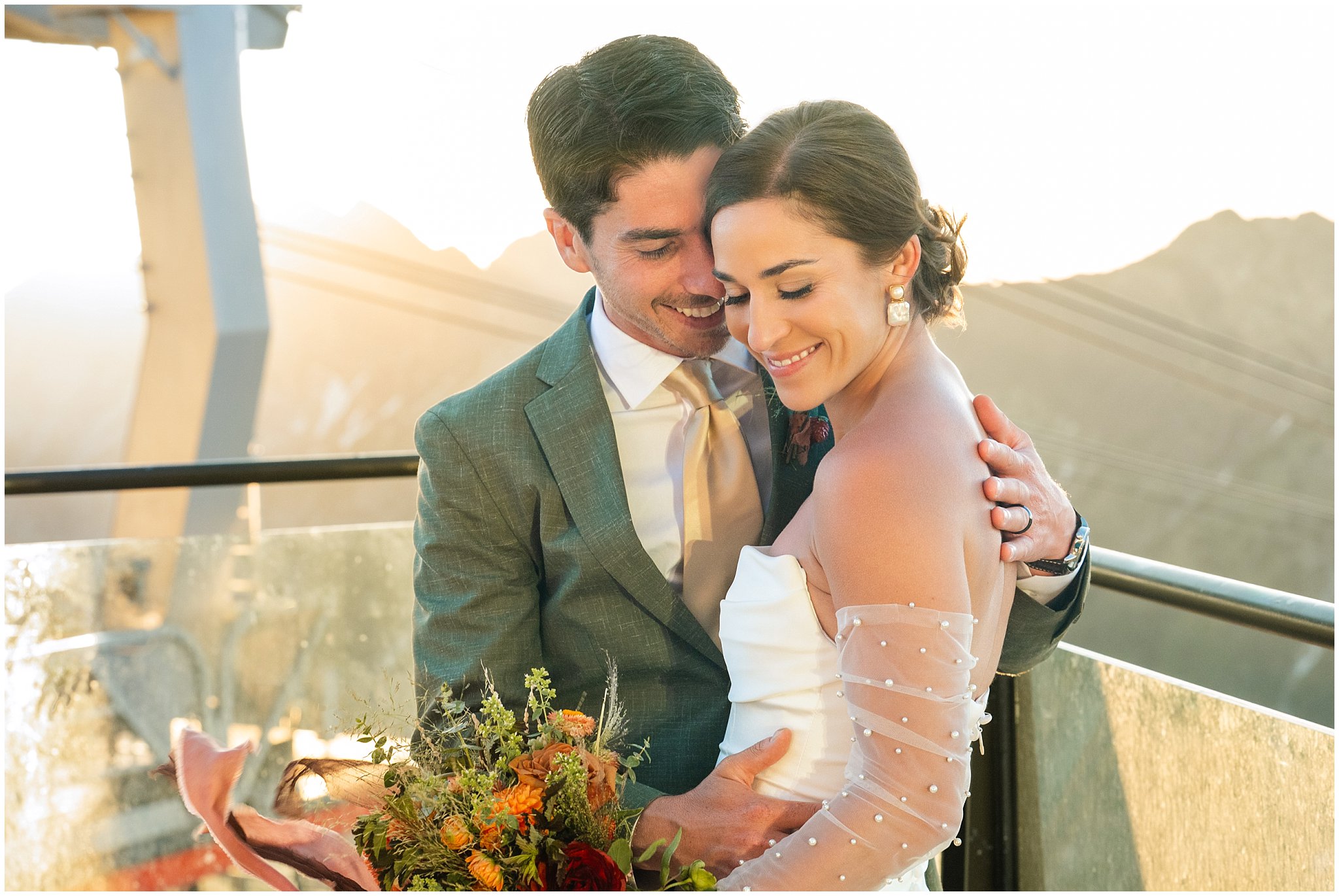 The bride and groom share moments together surrounded by the mountain peaks. Groom wearing a sage green suit and golden tie, bride in a strapless dress with gloves and veil | Snowbird Summit Summer Wedding | Jessie and Dallin Photography
