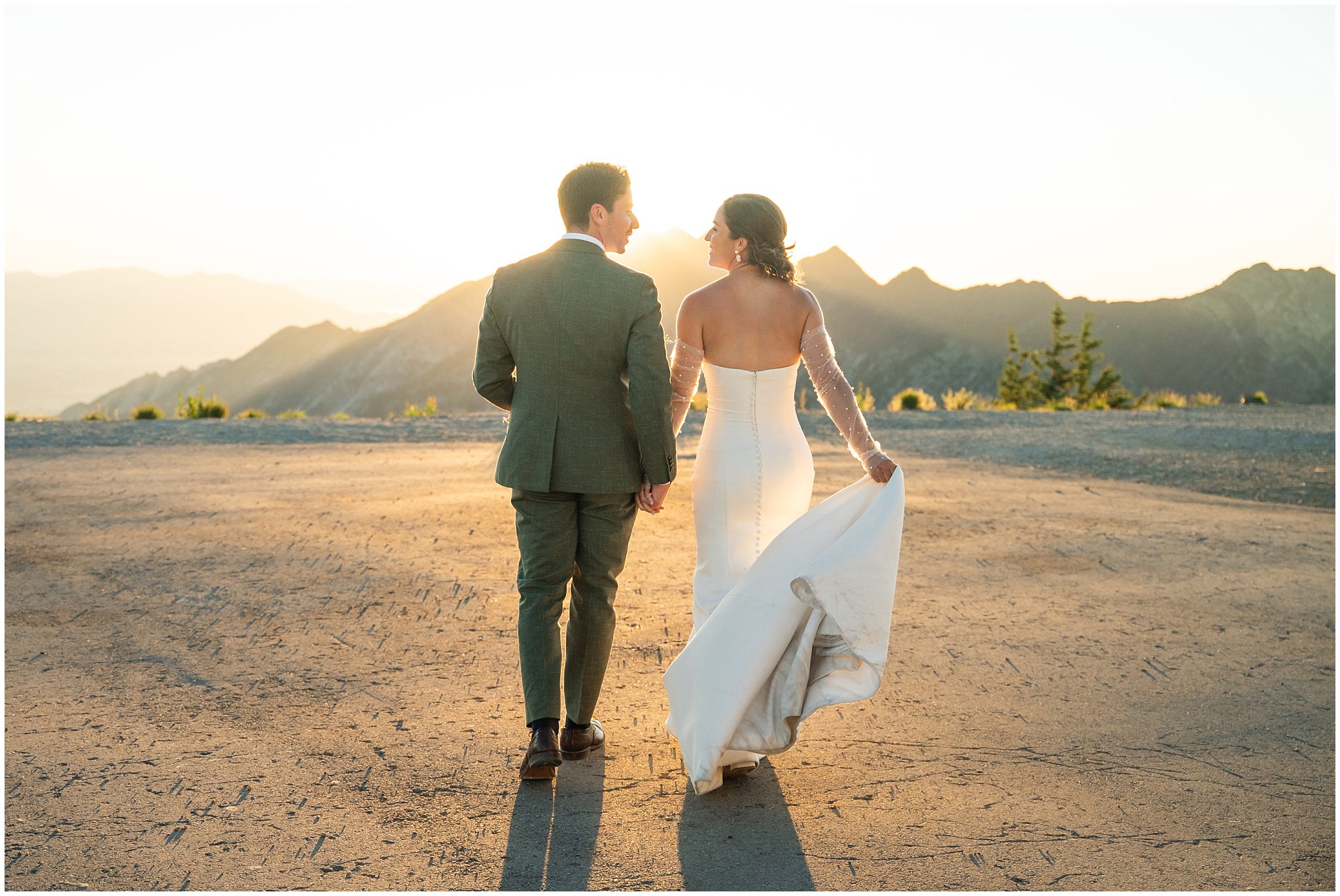 The bride and groom share moments together surrounded by the mountain peaks. Groom wearing a sage green suit and golden tie, bride in a strapless dress with gloves and veil | Snowbird Summit Summer Wedding | Jessie and Dallin Photography