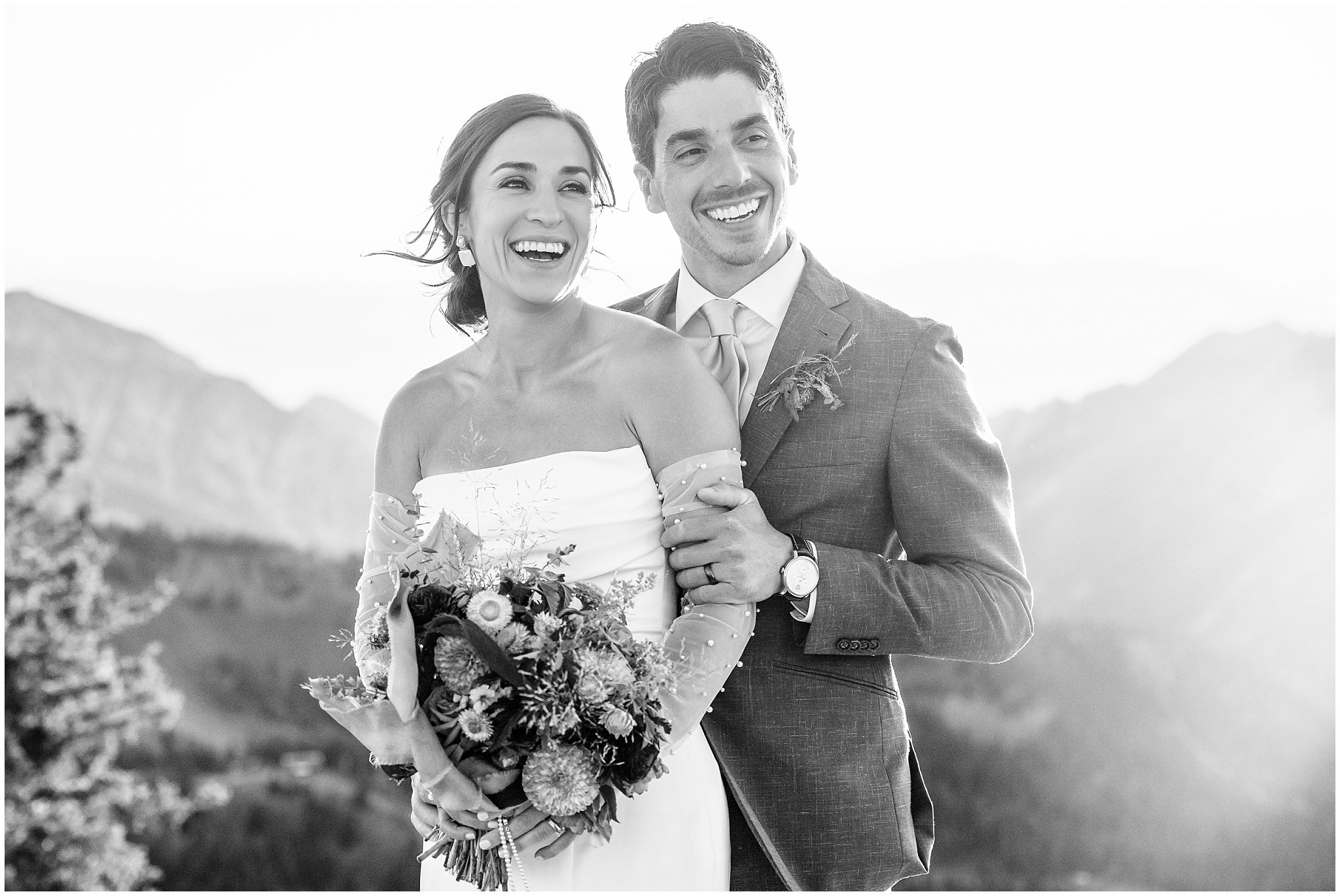 The bride and groom share moments together surrounded by the mountain peaks. Groom wearing a sage green suit and golden tie, bride in a strapless dress with gloves and veil | Snowbird Summit Summer Wedding | Jessie and Dallin Photography