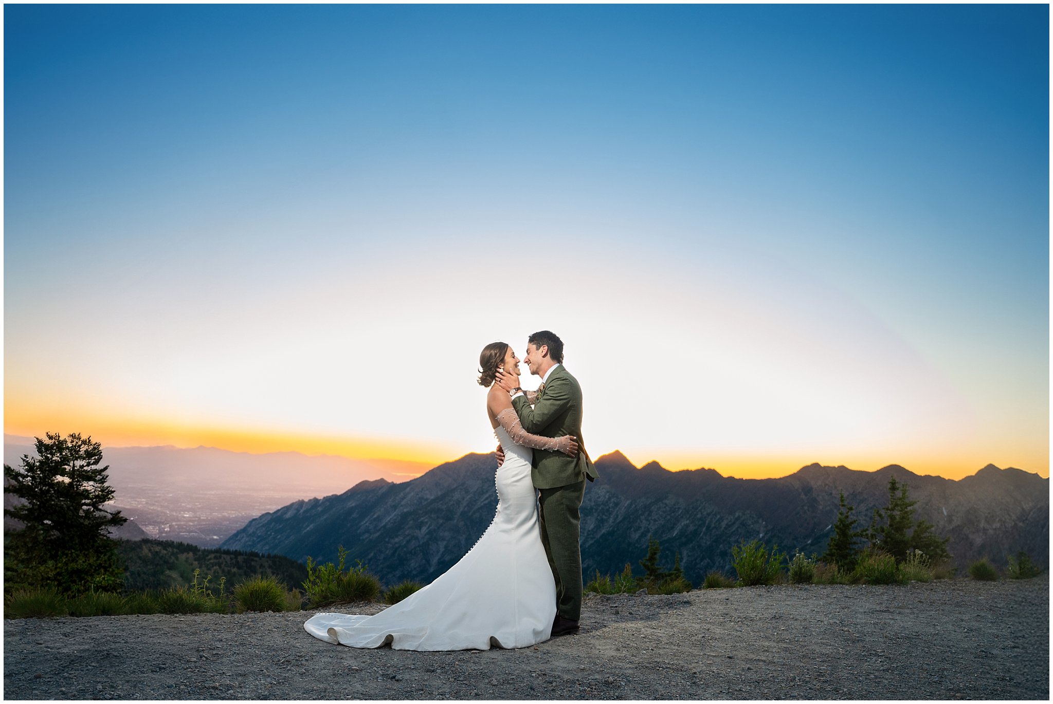 The bride and groom share moments together surrounded by the mountain peaks and a golden sunset and Alpen glow. Groom wearing a sage green suit and golden tie, bride in a strapless dress with gloves and veil | Snowbird Summit Summer Wedding | Jessie and Dallin Photography